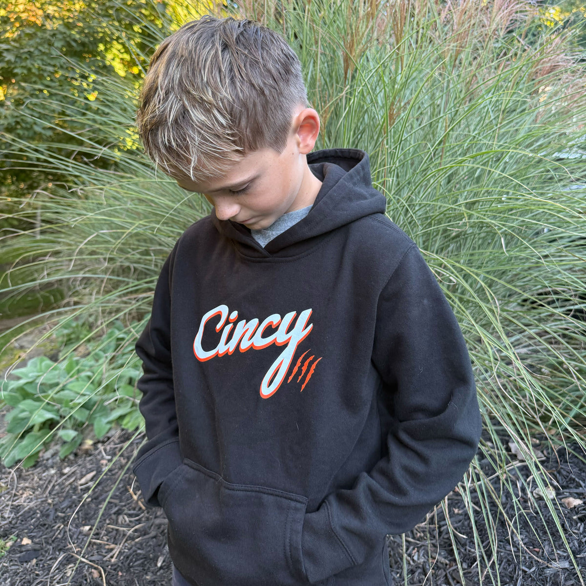 Youth model wearing the black Cincy hoodie outdoors