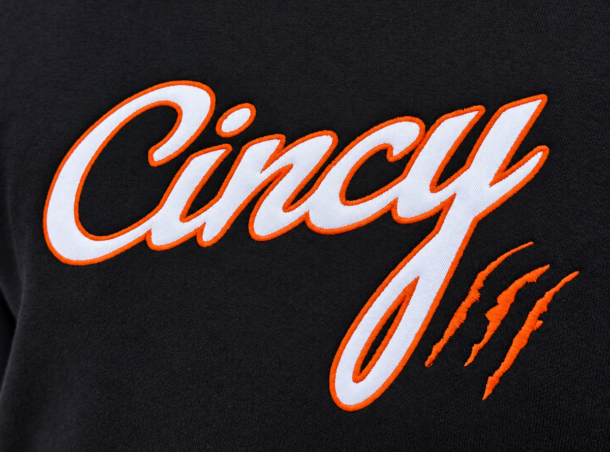 White Cincy script logo and orange claw-mark embroidery on black hoodie