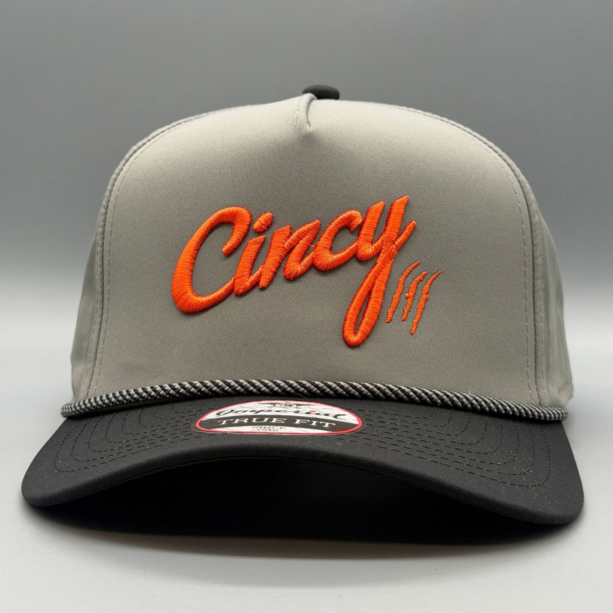 Front view of the grey and black OG 5 Panel hat with puffed orange Cincy script logo