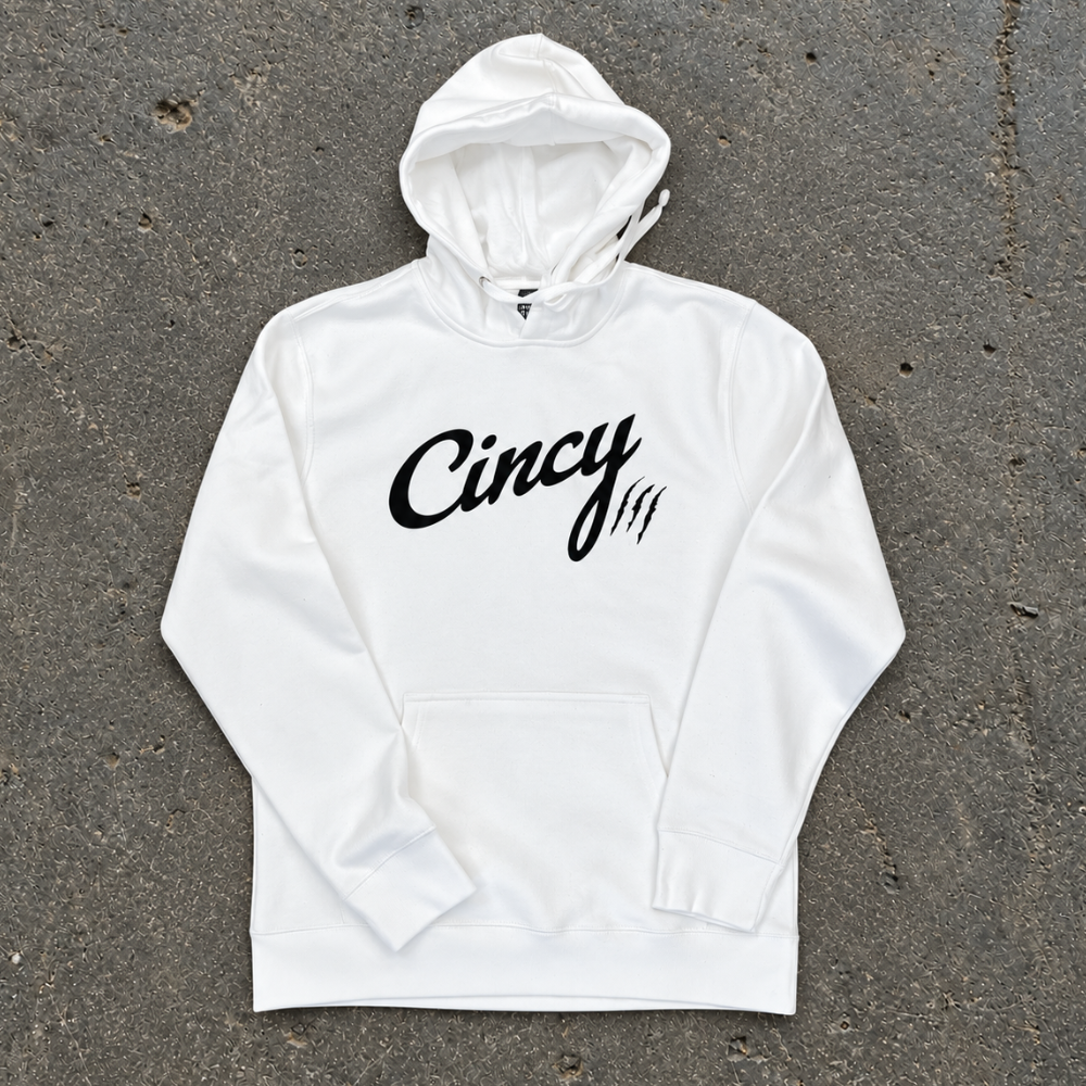 White pullover hoodie with black Cincy script logo and claw slashes, flat lay on concrete
