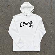 White pullover hoodie with black Cincy script logo and claw slashes, flat lay on concrete