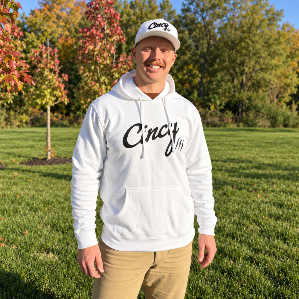 Man wearing the white Cincy hoodie with black logo outdoors in a park